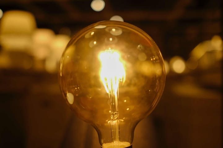 A glowing LED bulb emits warm light, surrounded by a soft bokeh background.
