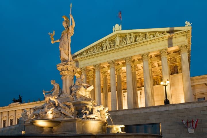 A historic building illuminated at night with a statue in the foreground.