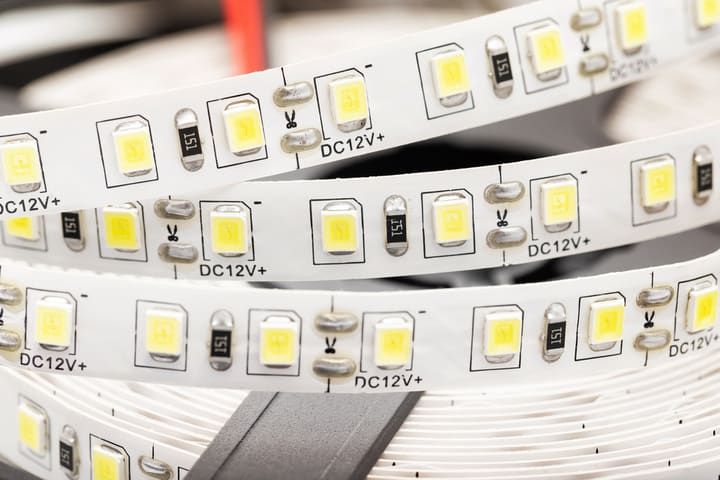 Close-up of flexible LED strip lights with yellow bulbs and electrical markings.