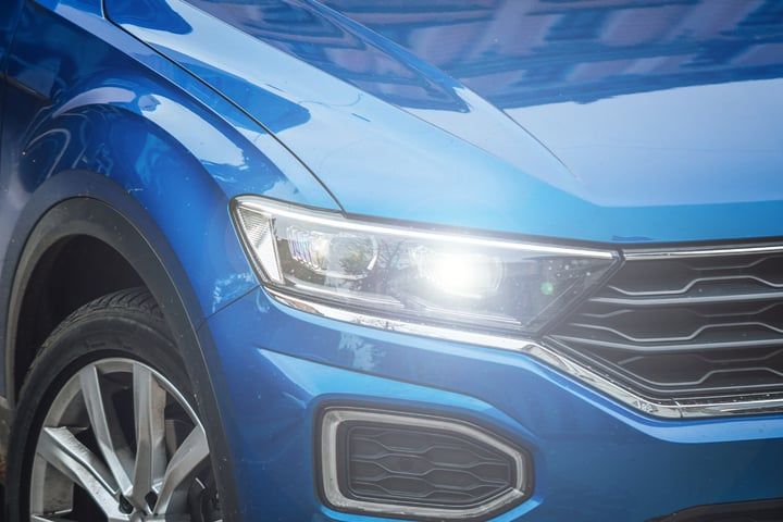 Close-up of a blue car's front light showing bright LED illumination.