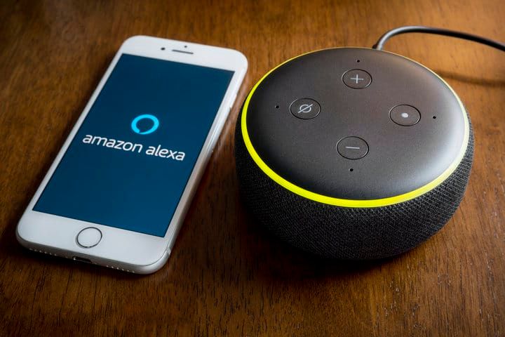 A smartphone displays the Amazon Alexa logo next to a smart speaker.