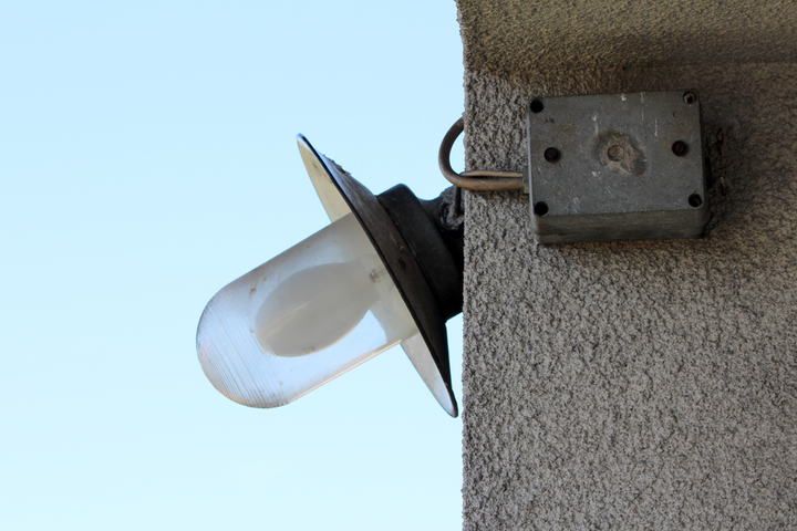 A vintage outdoor light fixture mounted on a textured wall.