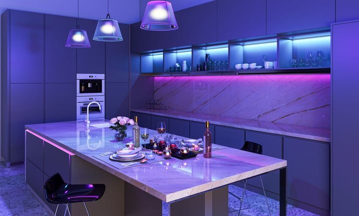 Modern kitchen featuring LED lights illuminating a marble countertop with decorative items.