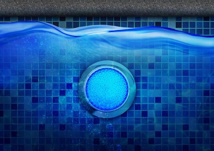 Round blue LED light underwater in a tiled swimming pool.