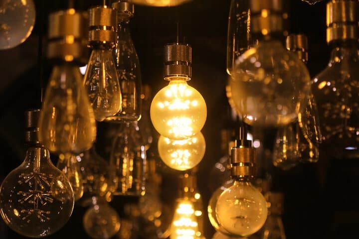 A cluster of various LED light bulbs glowing warmly in a dark setting.