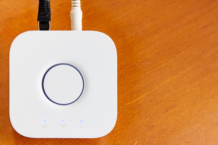 A white LED controller on a wooden surface with connected cables.