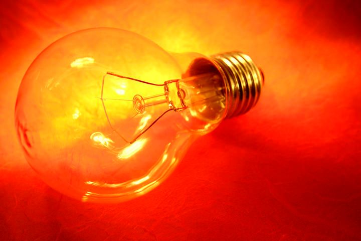 A glowing light bulb resting on a warm orange background.