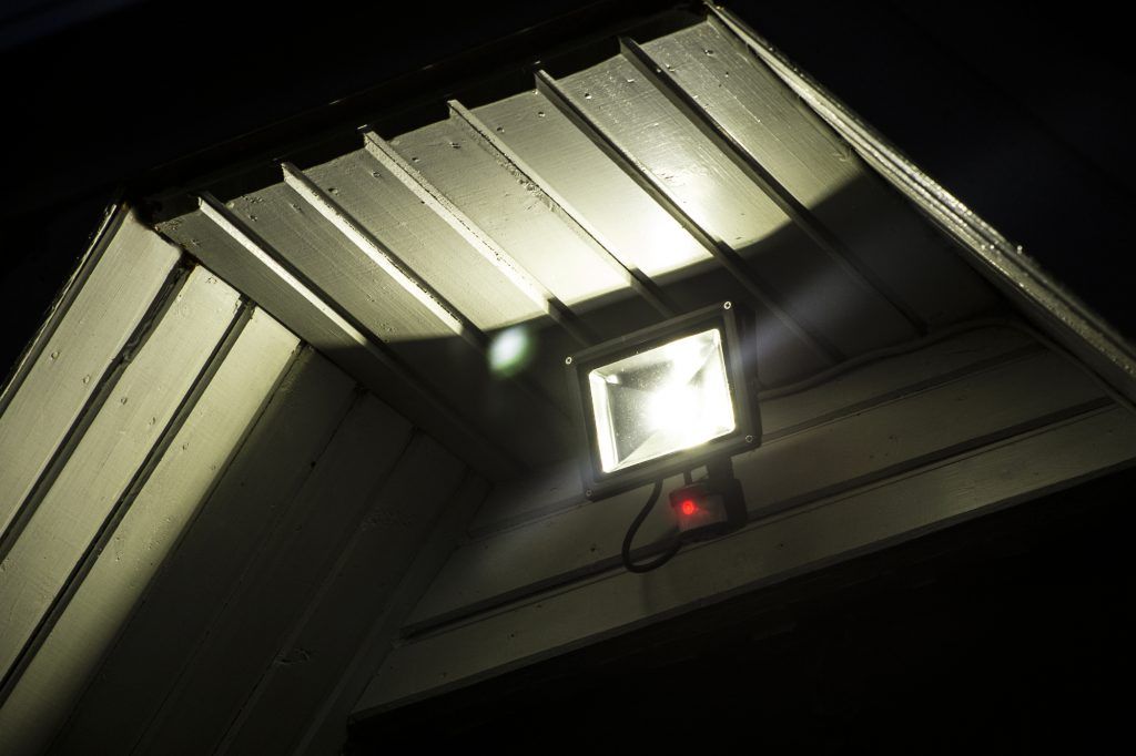 A square LED light fixture mounted on a wooden ceiling.