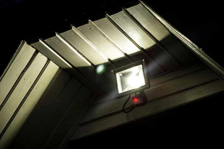 Bright LED floodlight mounted under a slanted roof at night.