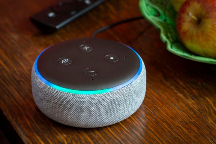 A round smart speaker with light indicators sits on a wooden table.