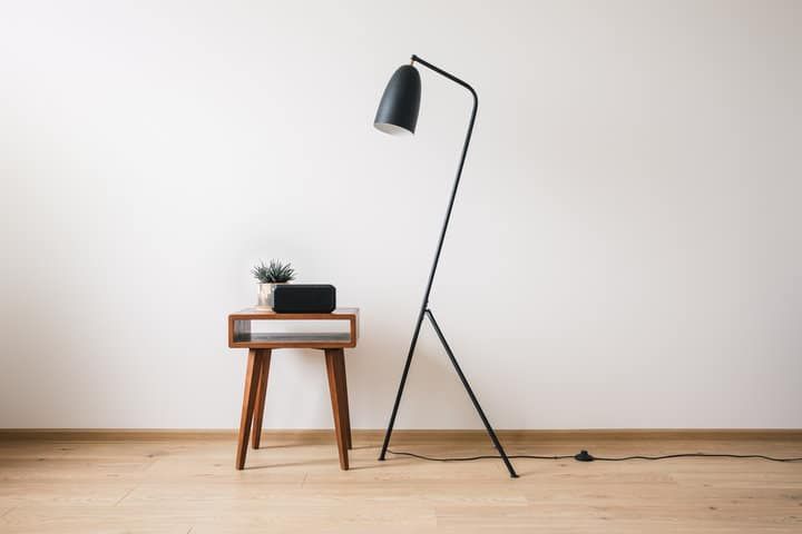A modern floor lamp stands beside a stylish wooden table with a plant.