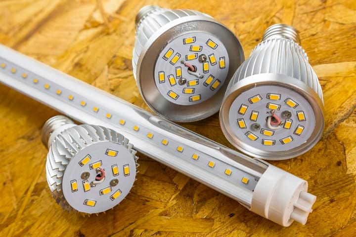 Three LED light bulbs and a tube on a wooden surface.