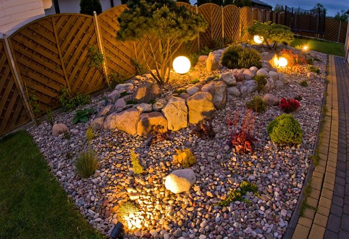 Garden scene with decorative boulders, plants, and illuminated LED globes.