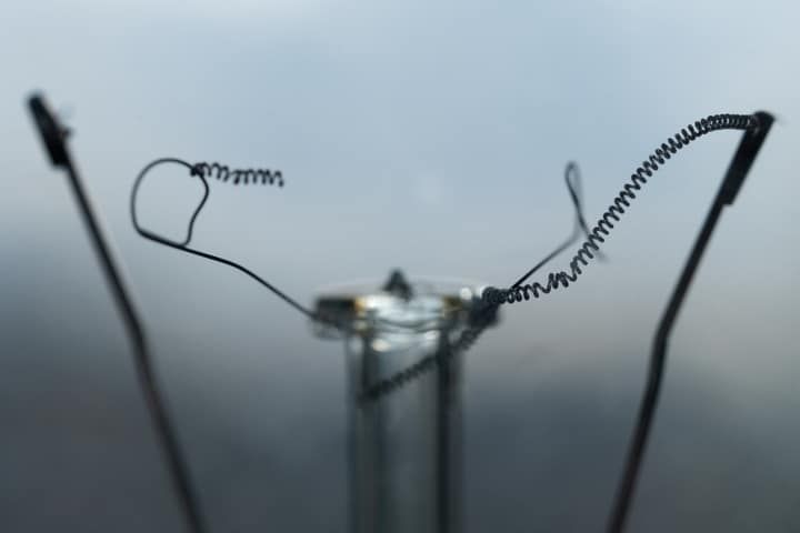 Close-up of a light bulb filament with twisted, coiled wires.