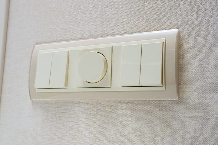 A wall switch panel with buttons including a dimmer control.