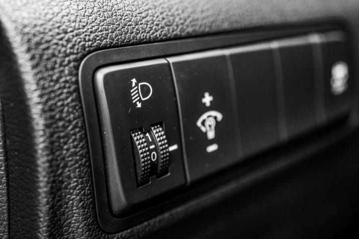 Close-up of a car interior control panel for headlights and brightness adjustment.