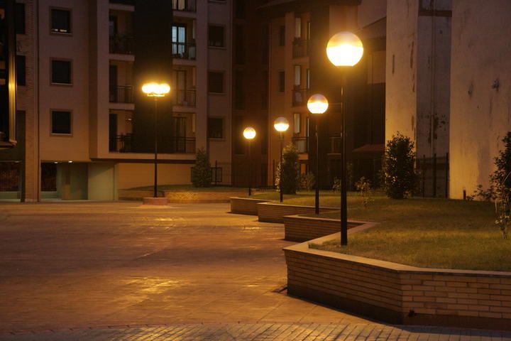 Illuminated pathway with round street lamps in a quiet urban area at night.