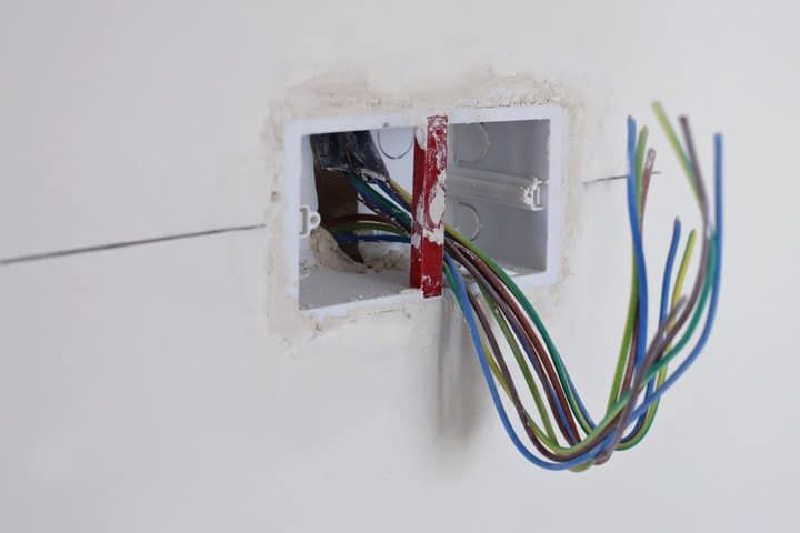 Electrical junction box with exposed wires in a wall opening.
