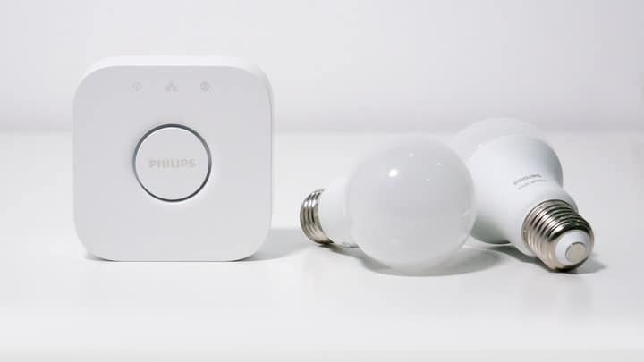 A smart lighting hub next to two white LED light bulbs.