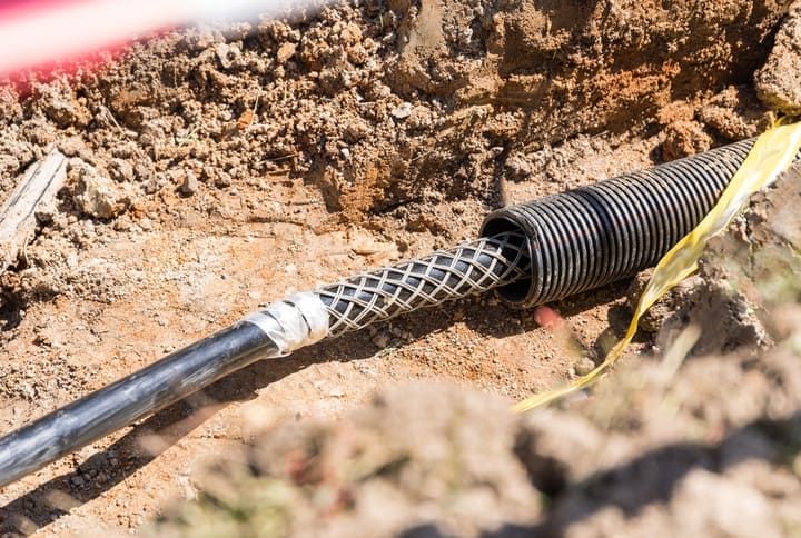 Underground electrical conduit with protective casing in a trench