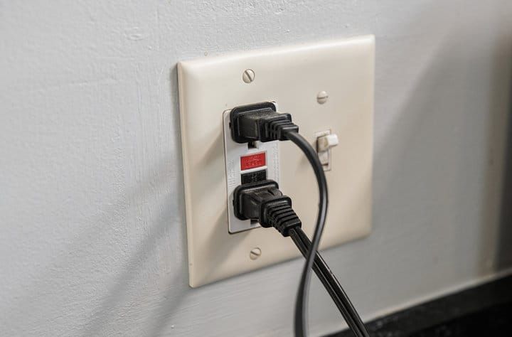 Electrical outlet with two plugged in cables on a wall.