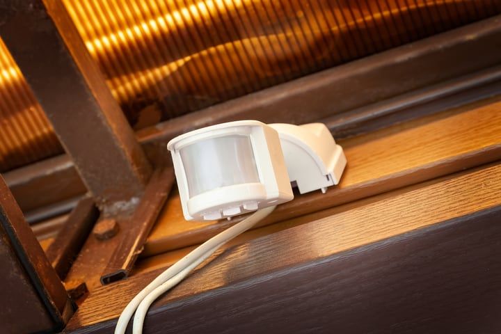 White motion sensor placed on a wooden surface near a window.