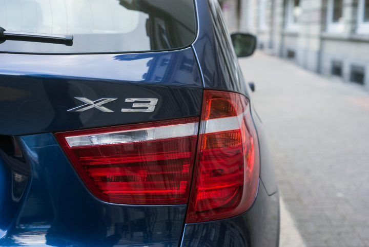 Close-up of a blue car's rear light and model badge on a street.