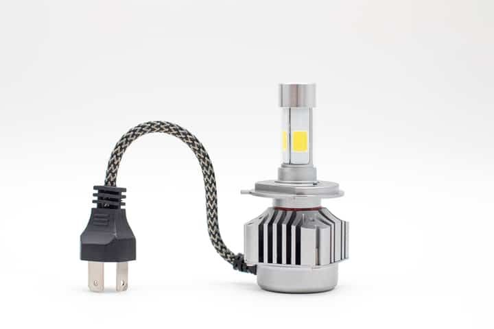 A compact LED light bulb with a wired connector and cooling fins.