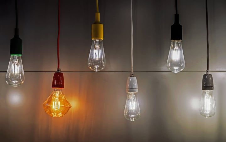 Various LED light bulbs hanging from colorful cords, some illuminated.