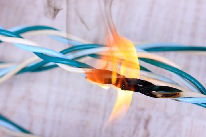 A close-up of burning electrical wires, showing flames and smoke.