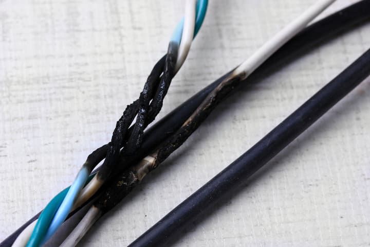 A close-up of damaged electrical wires showing burnt insulation and exposed conductors.