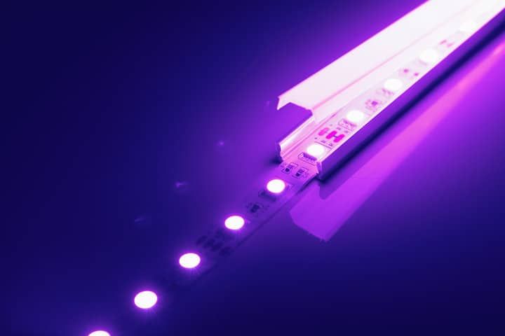 Purple LED strip lights with a sleek aluminum casing reflecting on a surface.