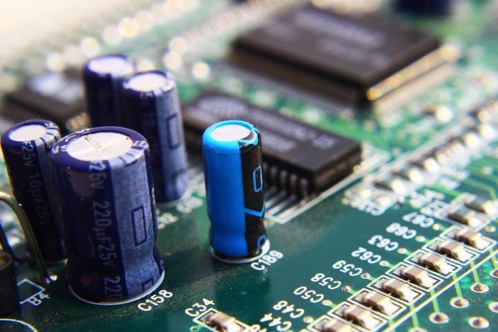 Close-up of electronic components, including capacitors and circuitry on a green board.