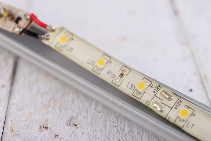Close-up of an LED strip showing connection points and glowing bulbs.