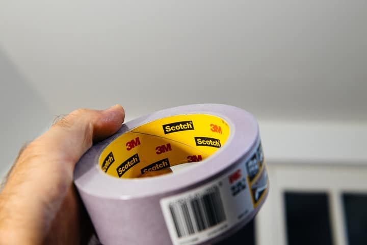 A person holding a roll of purple Scotch tape with branding visible.
