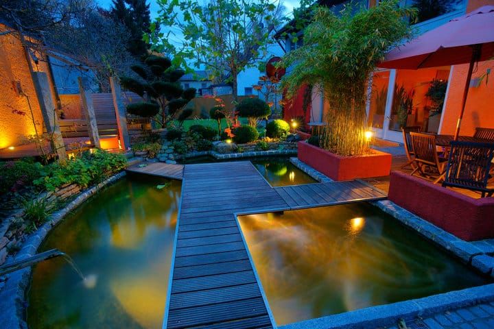 Tranquil garden scene at dusk with LED lights illuminating water features.