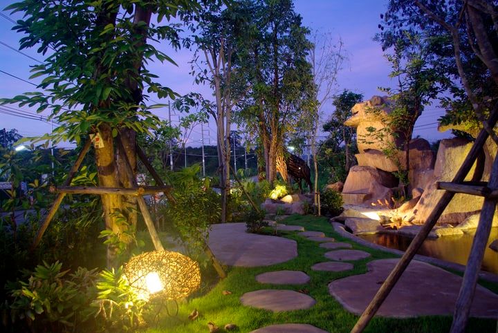 A beautifully lit garden path with decorative lights and natural landscaping.