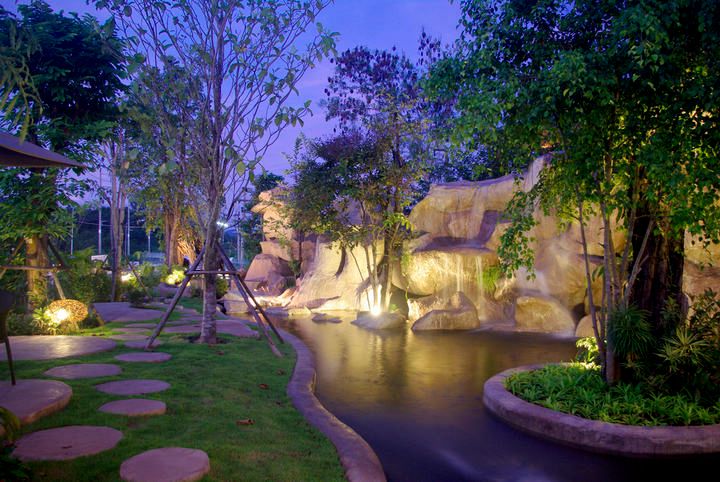 A serene garden scene featuring trees, a water feature, and LED lighting.