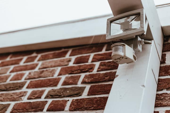A motion sensor LED light mounted on a textured brick wall.