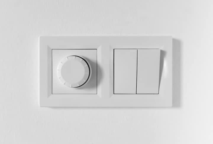 White wall switch and dimmer control panel on a plain wall.