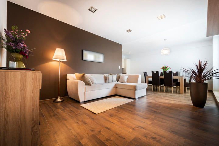 Bright living room with a sofa, lamp, and dining area illuminated by LED lights.