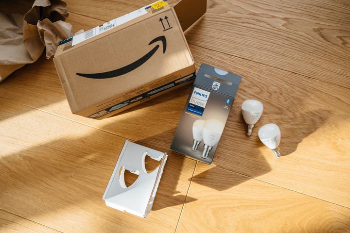 A cardboard box with an Amazon logo and LED bulbs on a wooden floor.