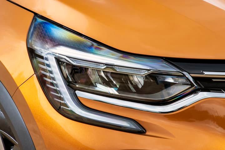 Close-up of a sleek car's LED headlight and orange bodywork.