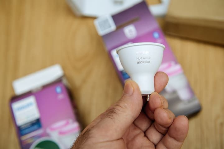 A person holding a white LED bulb with packaging in the background.