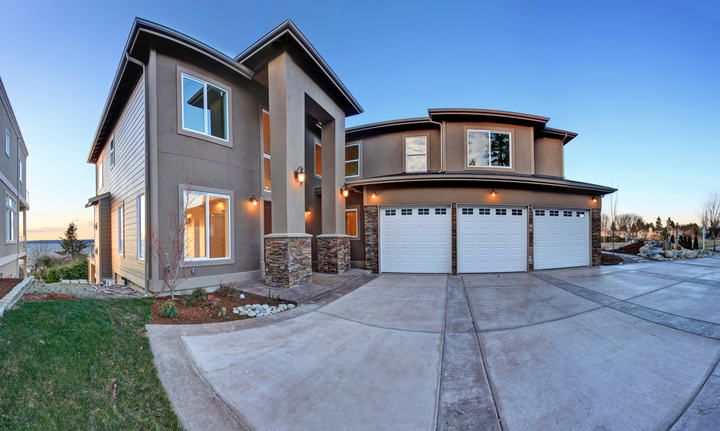 Modern two-story house with garage and landscaped yard, evening lighting.