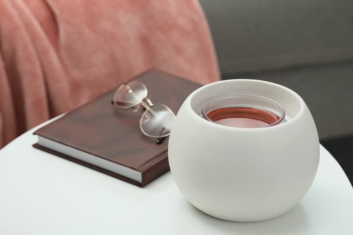 A round white LED light holder with a book and glasses nearby.