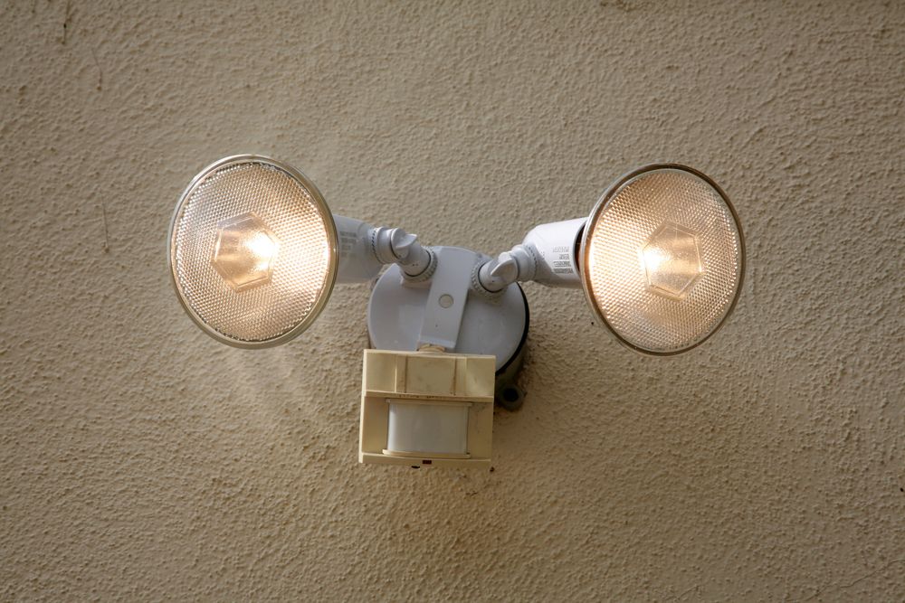 Two bright LED spotlights mounted on a textured wall.