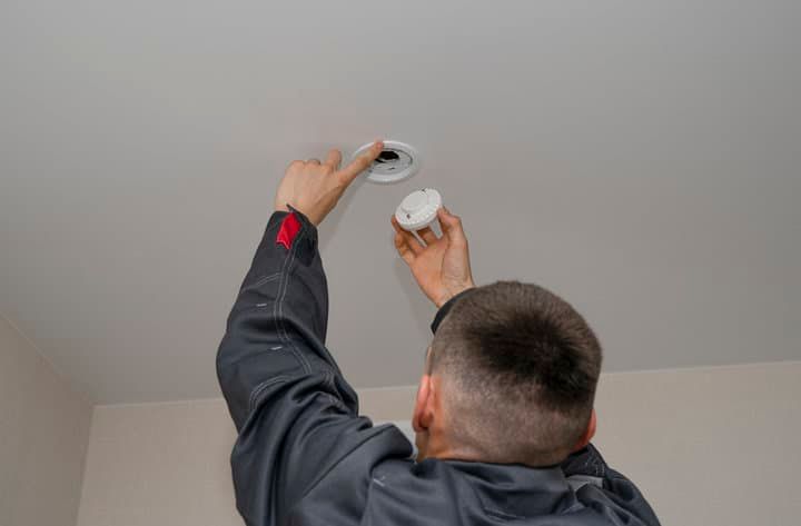 A person installing an LED light fixture in a ceiling.