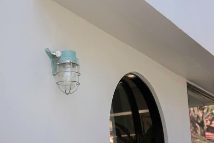 A mint green wall-mounted LED light fixture with a protective cage.