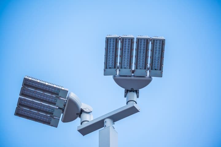 LED lighting fixture mounted on a tall pole against a clear blue sky.
